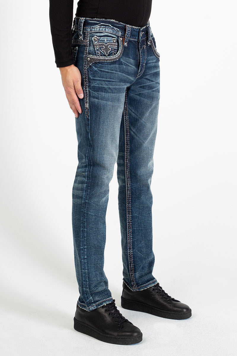 Herrenjeans in mittlerem Blau mit geradem Bein und leichter Waschung, kombiniert mit schwarzem Schuhwerk und langärmligem.