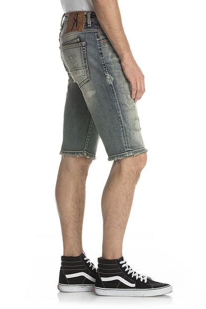 Verwaschene blaue Vintage-Shorts mit Destroyed-Details und lässigem Schnitt, kombiniert mit braunem Gürtel.